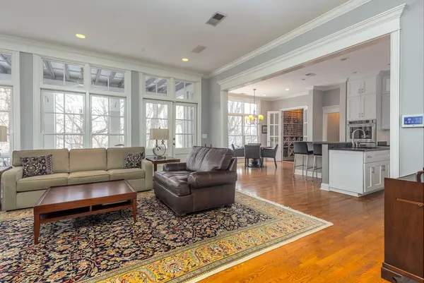 a kitchen with stainless steel appliances granite countertop a stove top oven a sink a dining table and chairs with wooden floor