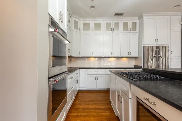 a kitchen with stainless steel appliances granite countertop a sink and a stove next to a window