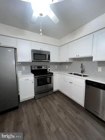 a kitchen with granite countertop a refrigerator a stove top oven a sink and dishwasher