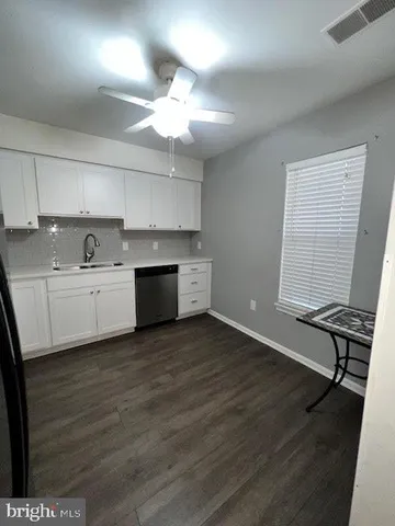 a view of a kitchen with sink and dishwasher with wooden floor