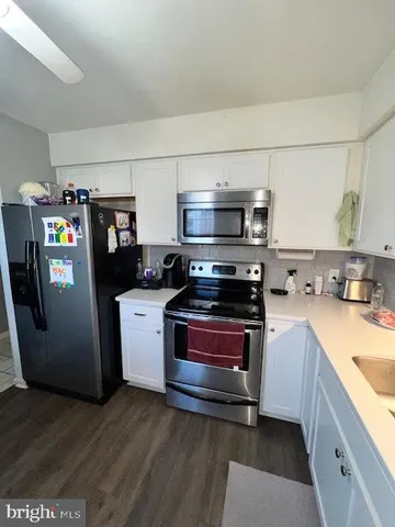 a kitchen with stainless steel appliances a stove a microwave a sink a refrigerator and wooden cabinets