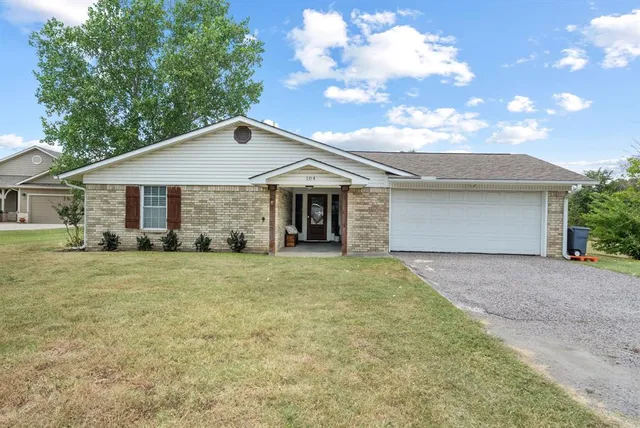 a front view of a house with a garden and trees