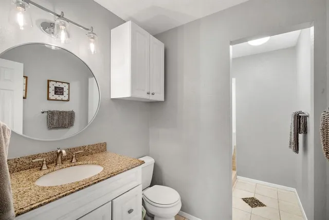 a bathroom with a granite countertop sink a toilet and a mirror
