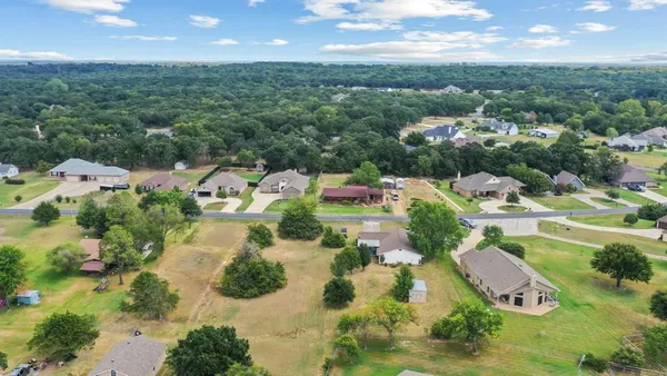 an aerial view of residential houses with outdoor space and trees