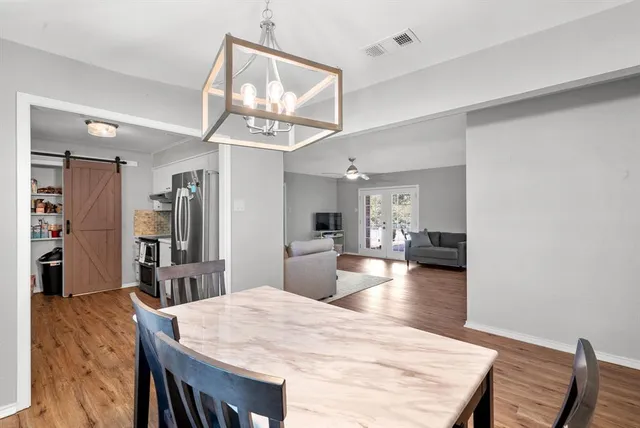 a view of a dining room and livingroom with furniture wooden floor a chandelier