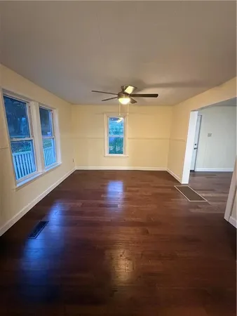 a view of an empty room with wooden floor and a window