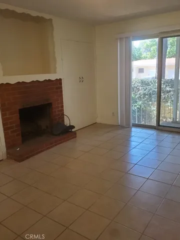 a view of an empty room with a fireplace and a window