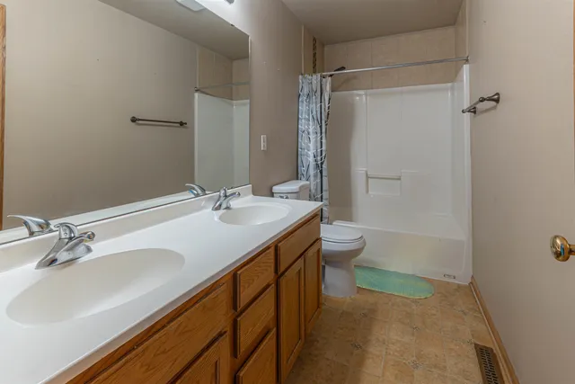 a bathroom with a granite countertop sink a toilet and shower