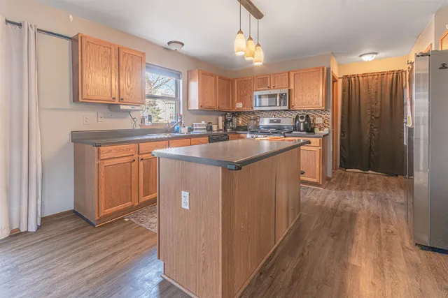 a kitchen with stainless steel appliances granite countertop a refrigerator a sink dishwasher a stove with wooden cabinets and floor