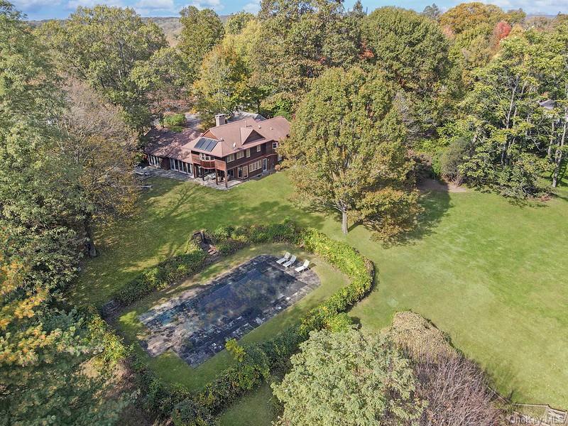 Aerial view of home, gunite pool, and expansive level lawn