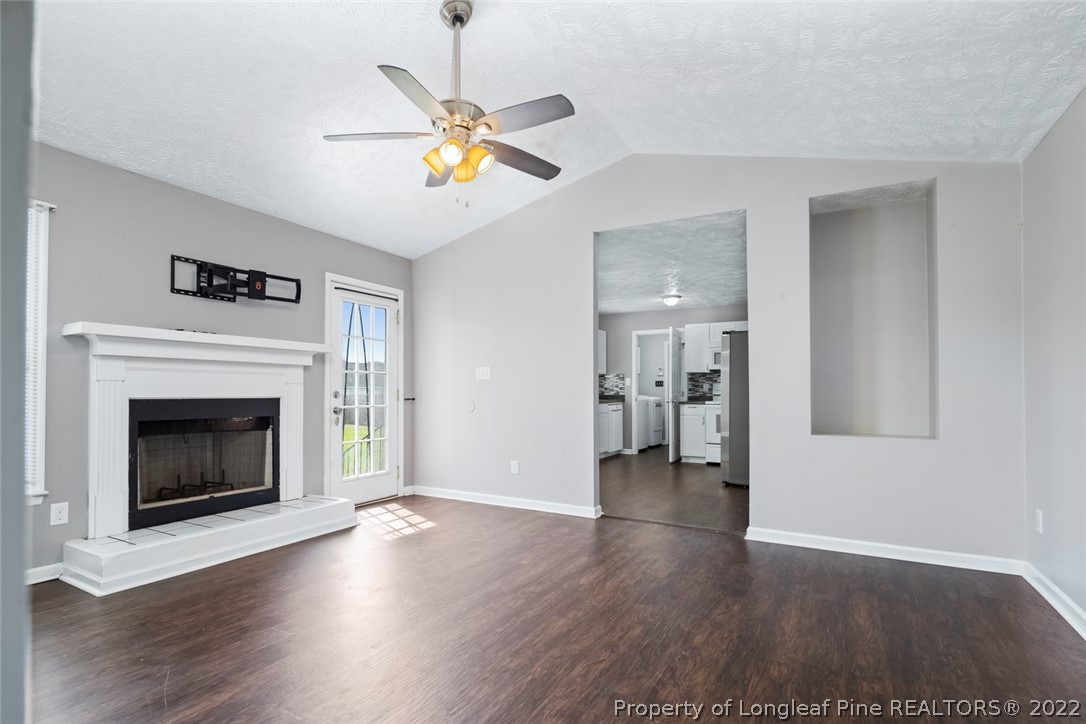 8209 Rockfish Road Raeford, NC 28376 - Photo 17 of 42 a view of an empty room with wooden floor fireplace and a window