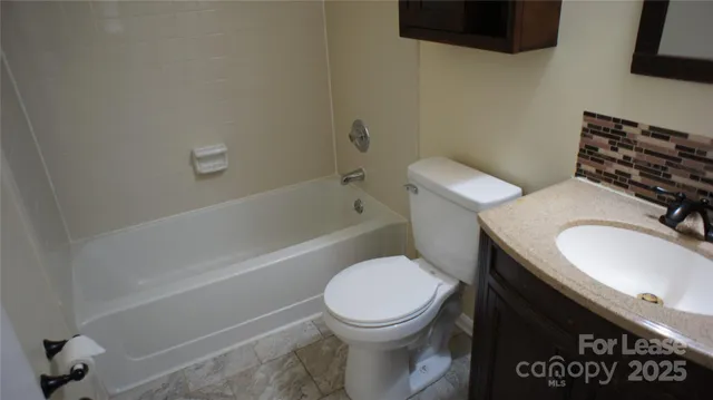 a bathroom with a granite countertop toilet sink and mirror