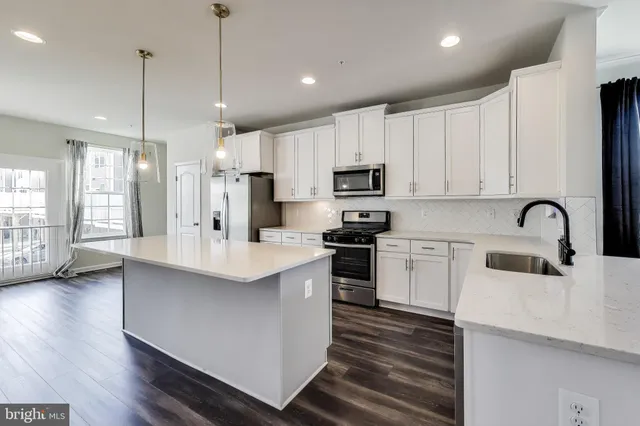 a kitchen with kitchen island white cabinets and stainless steel appliances
