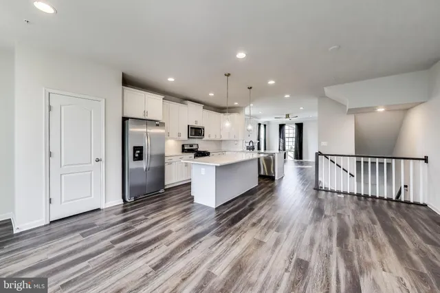 a large kitchen with a center island wooden floor stainless steel appliances and cabinets