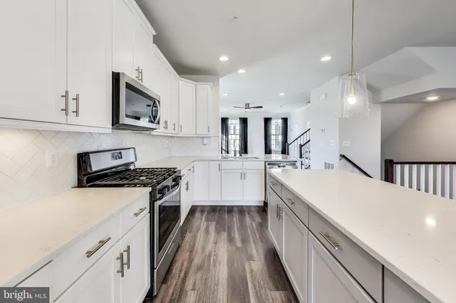 a large kitchen with stainless steel appliances granite countertop a lot of counter space and wooden floor