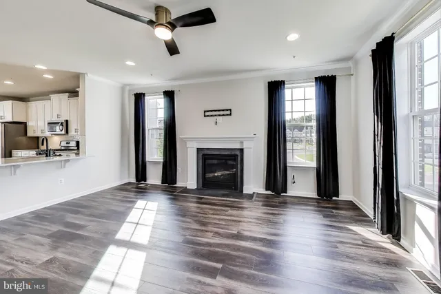 a view of an empty room with kitchen and a window