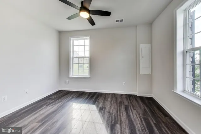 a view of empty room with wooden floor and fan