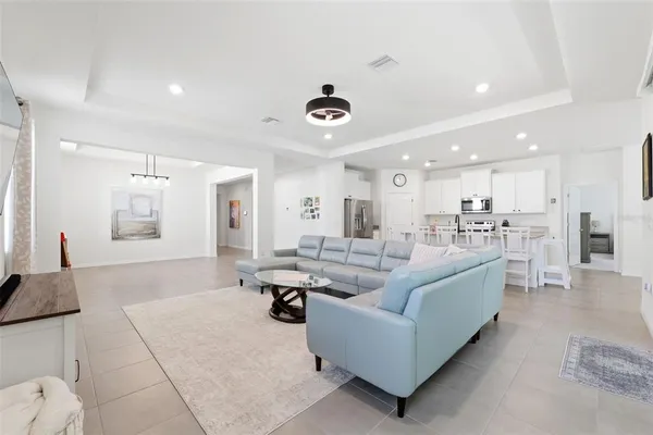 a kitchen with stainless steel appliances granite countertop a stove top oven a sink a refrigerator with white cabinets and wooden floor