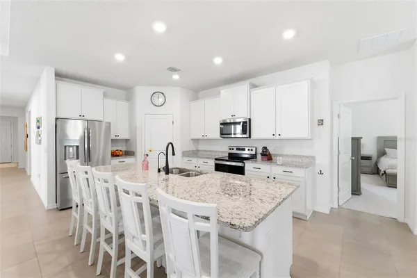 a kitchen with stainless steel appliances granite countertop a refrigerator a stove top oven a sink dishwasher and white cabinets