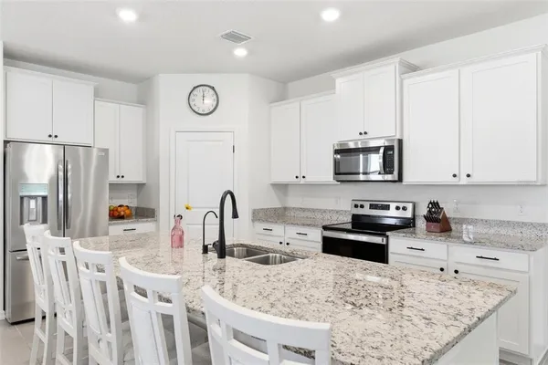 a large kitchen with granite countertop a sink a stove and cabinets