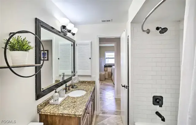a bathroom with a granite countertop shower a mirror and a sink