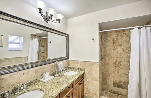 a bathroom with a granite countertop sink a mirror and a shower