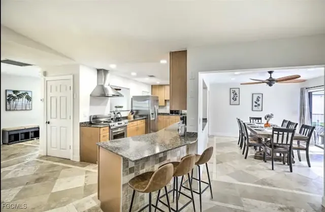 a kitchen with stainless steel appliances kitchen island granite countertop a table and chairs in it