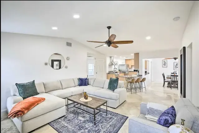 a living room with furniture kitchen view and a chandelier