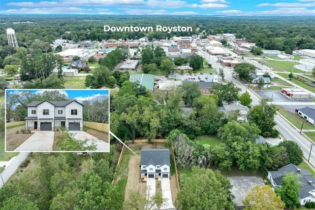 an aerial view of residential houses with outdoor space and trees