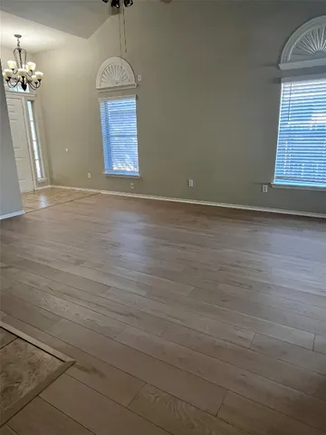 an empty room with wooden floor windows and glass door