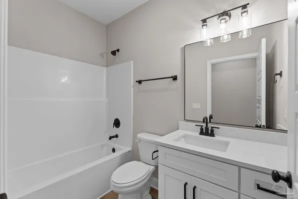 a bathroom with a toilet a sink a mirror a bathtub and vanity