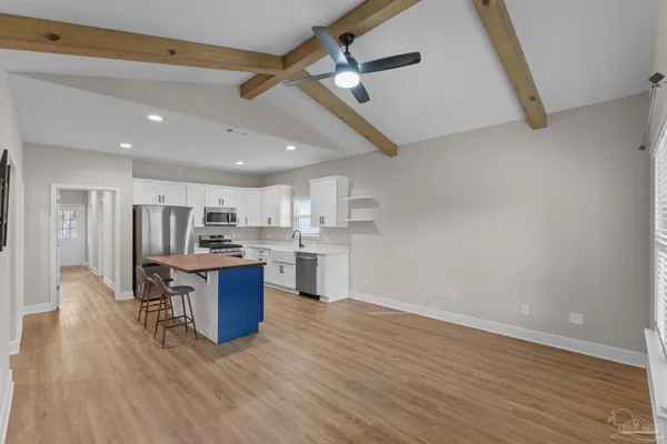 a kitchen with kitchen island wooden floors appliances and cabinets