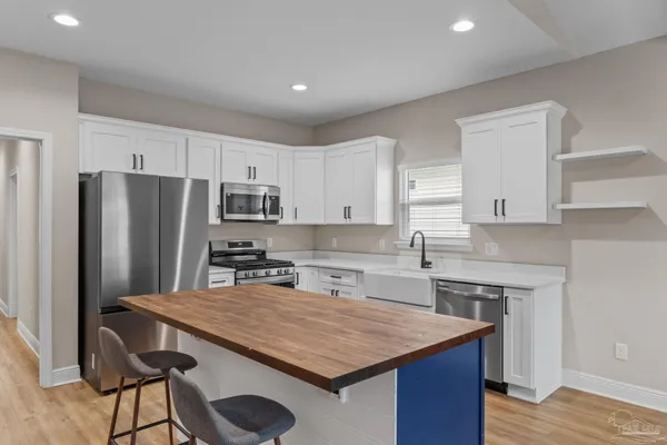 a kitchen with stainless steel appliances granite countertop a kitchen island a stove a refrigerator a sink and a cabinets