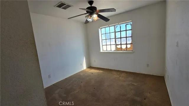 an empty room with windows and fan