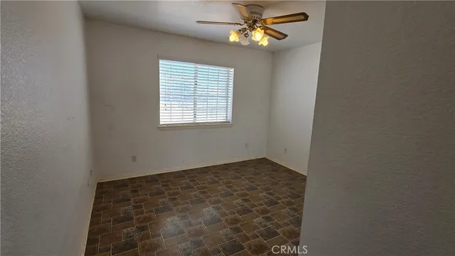 an empty room with windows and fan