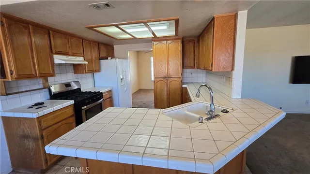 a kitchen with stainless steel appliances wooden cabinets a stove a sink and a refrigerator