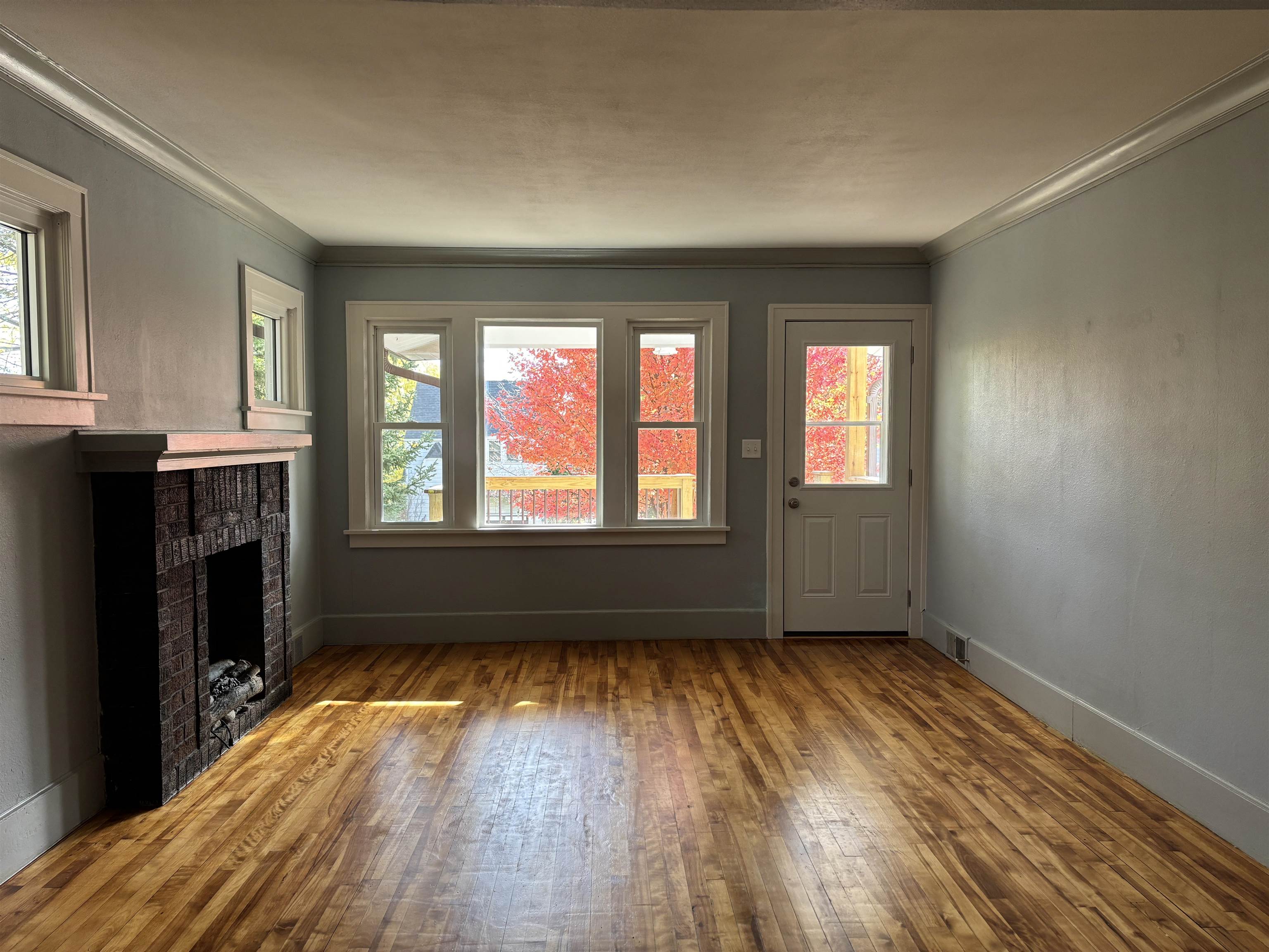 2515 Jefferson Street Duluth, MN 55812 - Photo 9 of 25 Unfurnished living room featuring healthy amount of natural light, hardwood / wood-style flooring, crown molding, and a brick fireplace