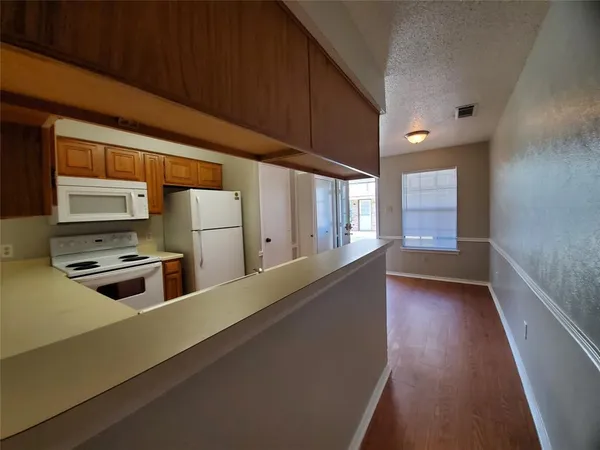 a kitchen with stainless steel appliances a stove a sink a refrigerator white cabinets and wooden floor