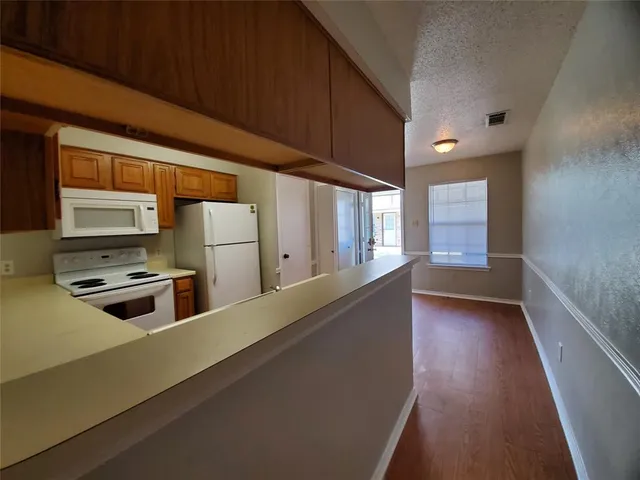 a kitchen with stainless steel appliances a stove a sink a refrigerator white cabinets and wooden floor