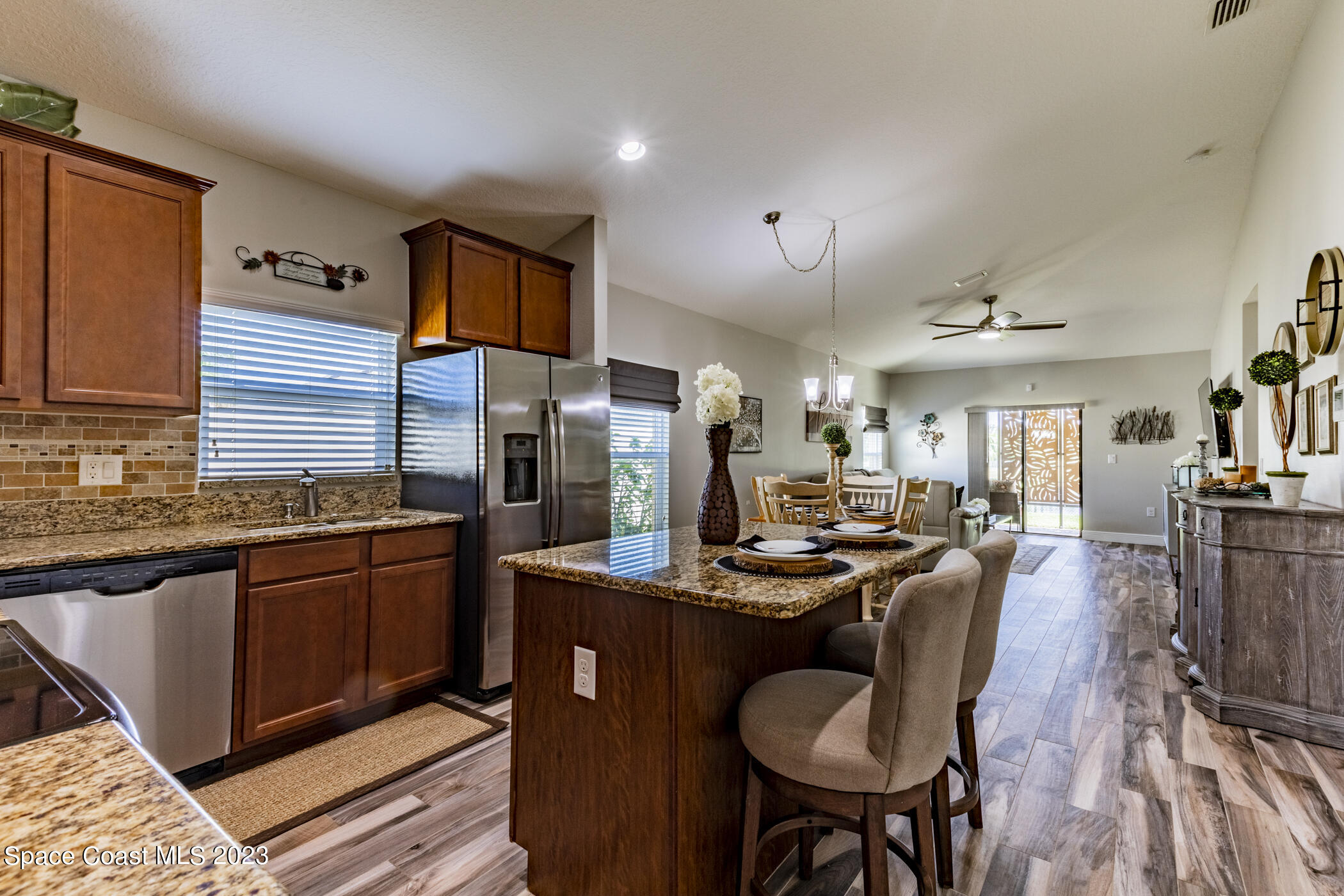 2995 Louetta Circle Melbourne, FL 32901 - Photo 16 of 42 a kitchen with stainless steel appliances granite countertop a refrigerator a sink dishwasher a dining table and chairs with wooden floor