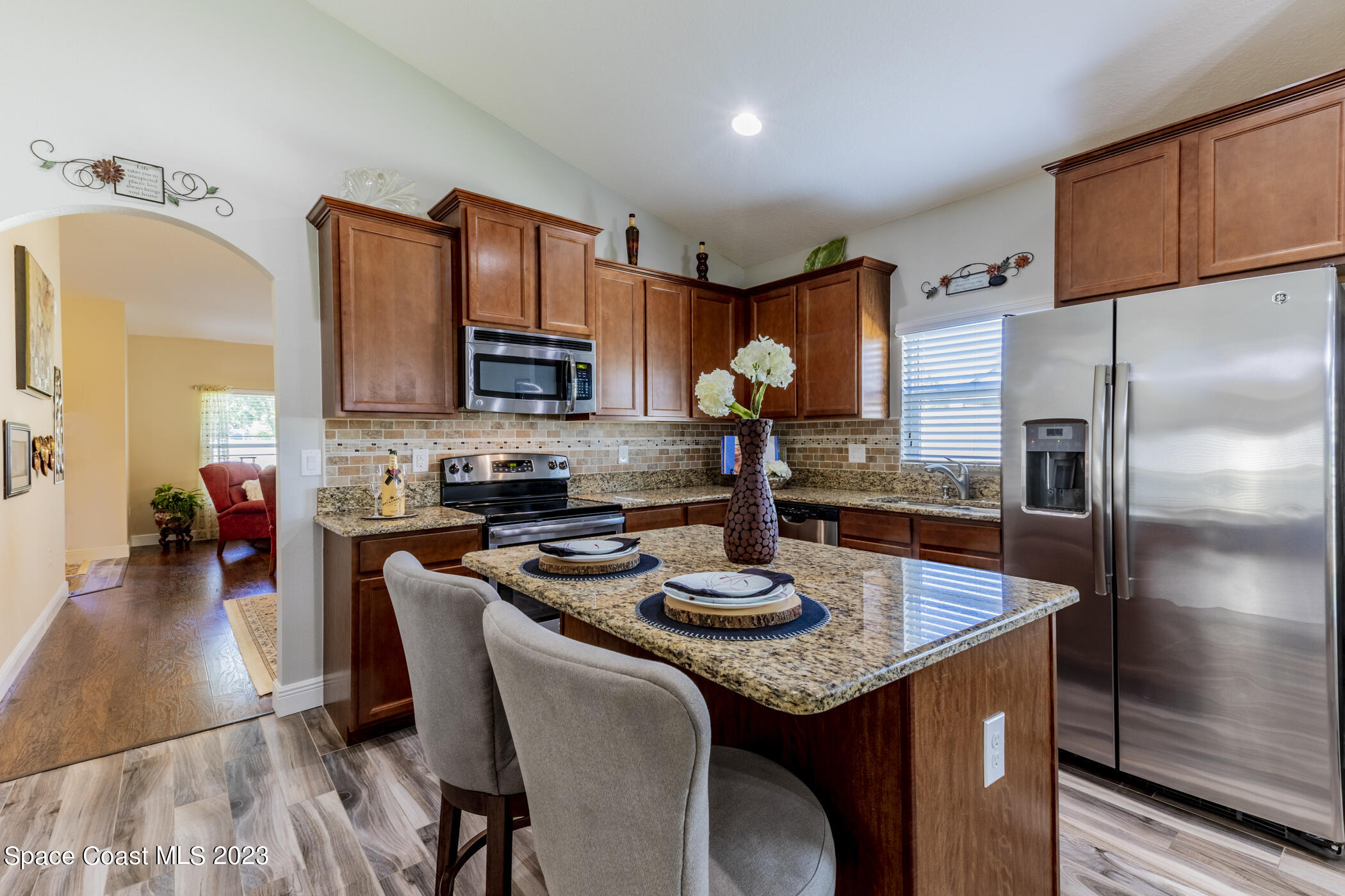 2995 Louetta Circle Melbourne, FL 32901 - Photo 17 of 42 a kitchen with stainless steel appliances granite countertop a sink a stove a refrigerator cabinets and a dining table