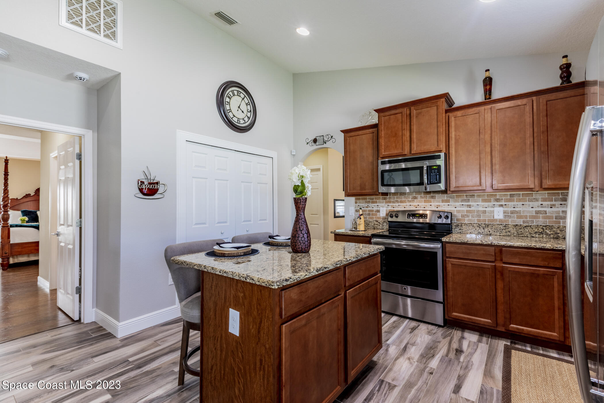 2995 Louetta Circle Melbourne, FL 32901 - Photo 18 of 42 a kitchen with stainless steel appliances granite countertop a stove top oven a sink dishwasher and a refrigerator with wooden floor