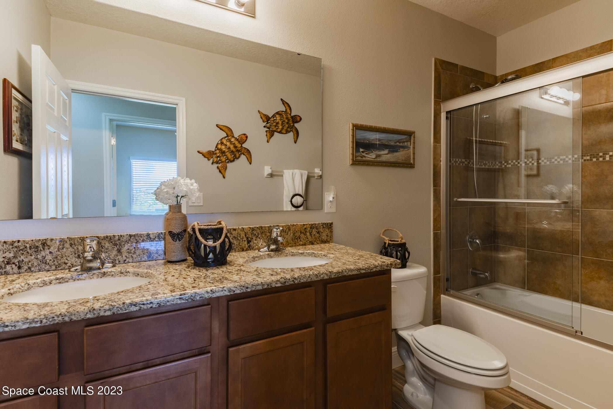 2995 Louetta Circle Melbourne, FL 32901 - Photo 32 of 42 a bathroom with a granite countertop sink a toilet a mirror a vanity and shower