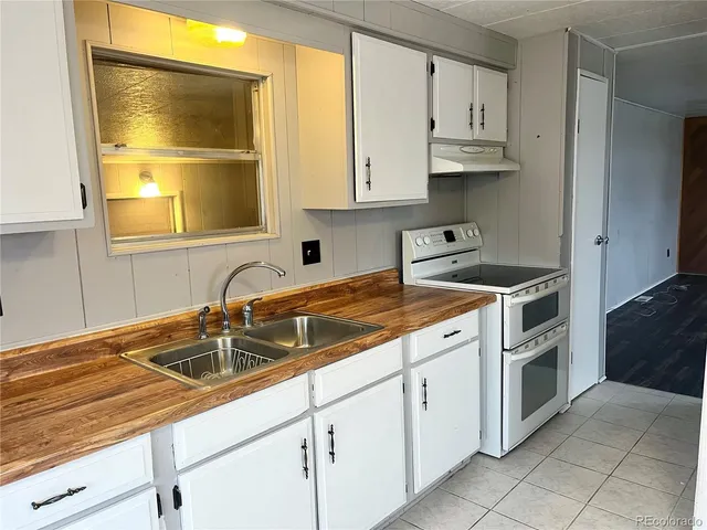 a large white kitchen with a large window a sink and appliances