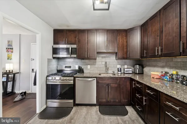 a kitchen with stainless steel appliances a stove a sink cabinets and a refrigerator