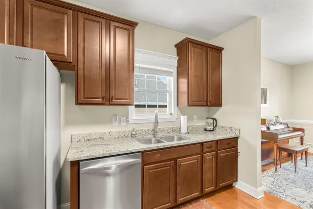 a kitchen with stainless steel appliances granite countertop wooden cabinets a sink and a refrigerator