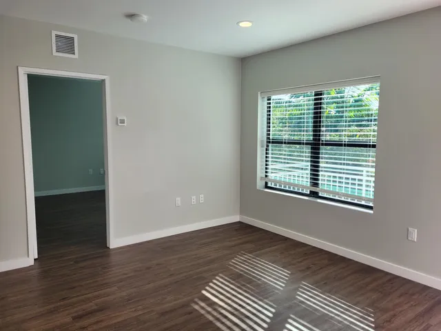 a view of an empty room with wooden floor and a window