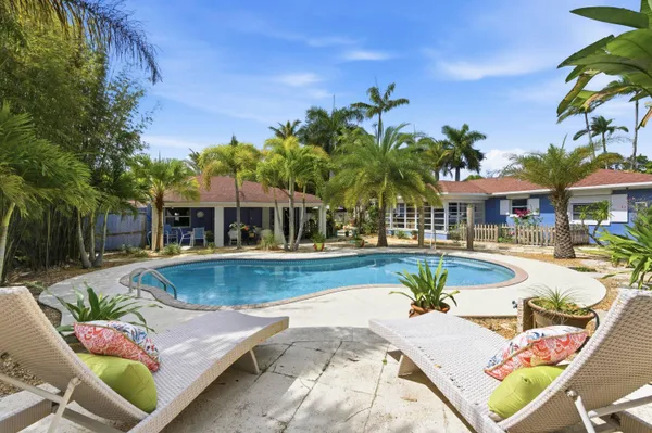 a view of a swimming pool with couches chairs in patio