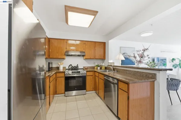 a kitchen with stainless steel appliances granite countertop a stove a sink dishwasher and a refrigerator