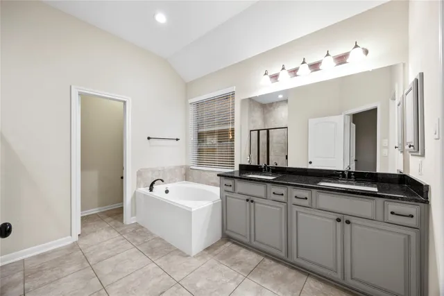 a spacious bathroom with a sink double vanity granite tub and mirror